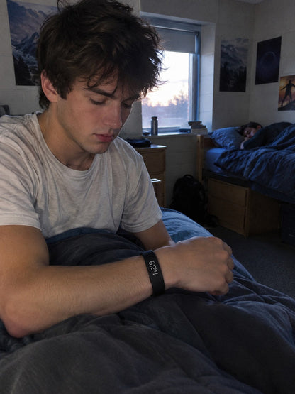 A student wakes quietly wearing the ECDF wristband while his roommate sleeps
