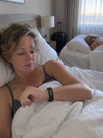 A woman wakes quietly wearing the ECDF wristband in a shared hotel room