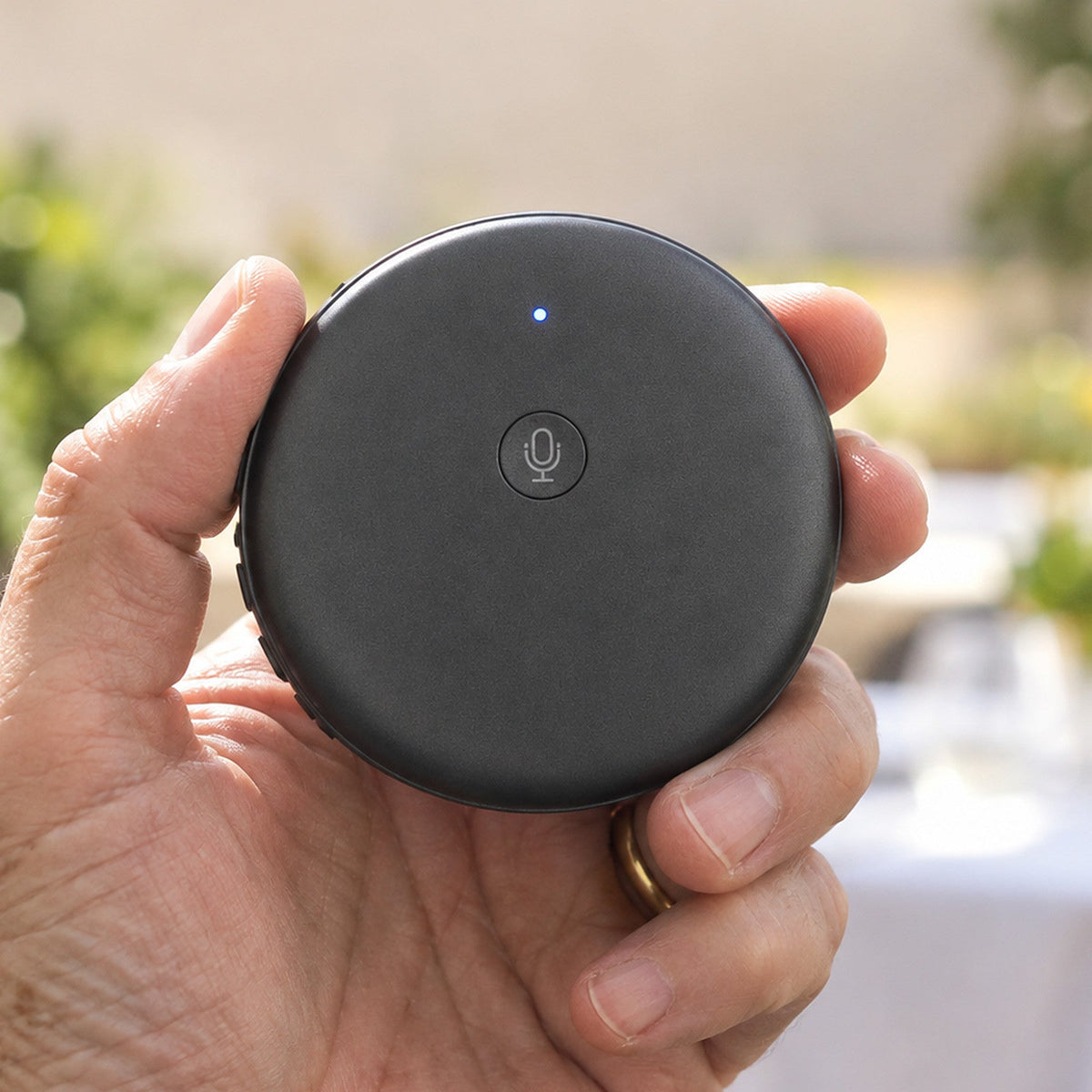 The round ECDF translator with its single button, held in the palm of a hand